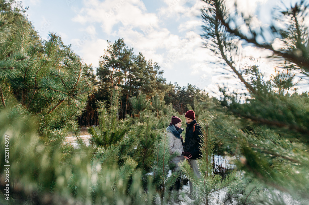 Young hipster couple hugging each other in winter park.