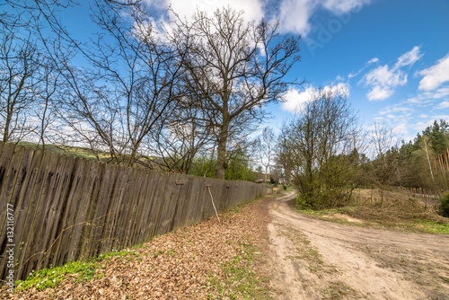 Rural road and wooden fence, spring landscape