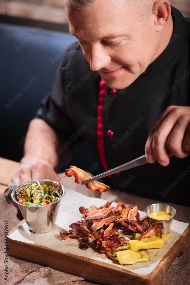 Overjoyedman eating bacon in restaurant