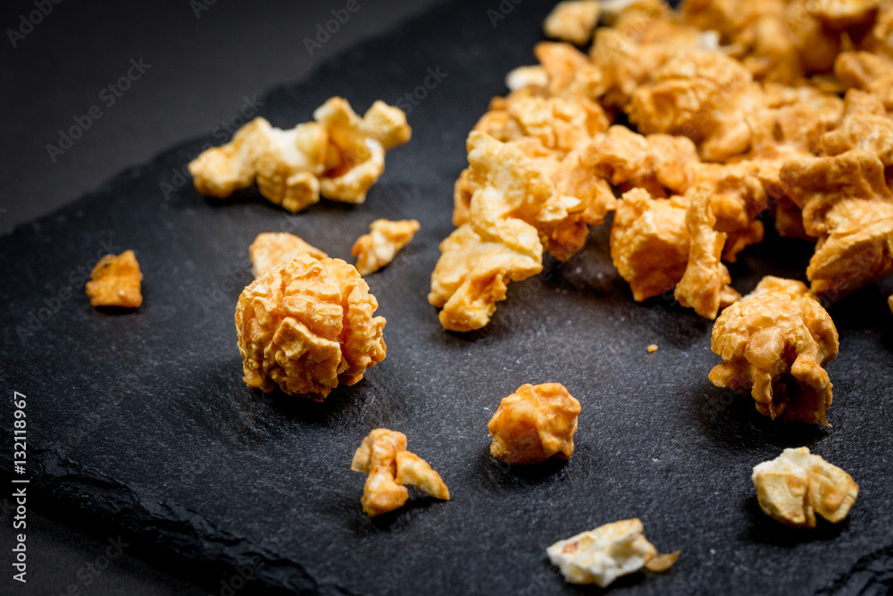 Caramel Cream popcorn on stone plate black background. Caramel Cream popcorn on stone plate black background.