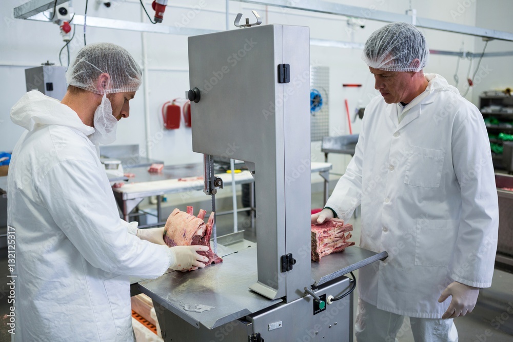 Butchers cutting raw meat on a band saw machine StockFoto Adobe Stock