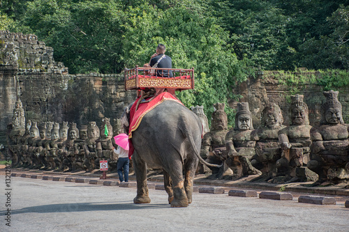 A tourist is riding on the back of elephant on the street to Angkor Thom, Siem Reap, Cambodia  © tananyaa