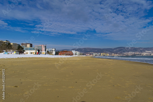 Snowy beach and sea at winter with blue sky