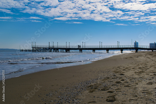 Beach wharf at winter with snowy sands and blue sky