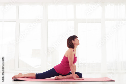 Mature lady performing a yoga element on a mat