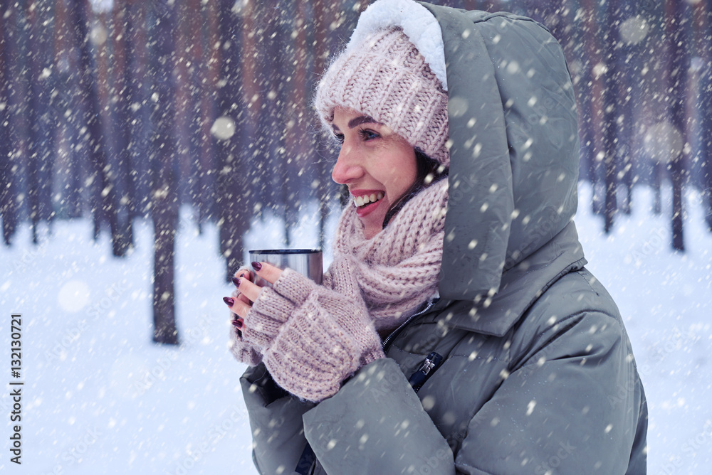 Romantic woman in knitted cap and scarf enjoying a cup of hot te