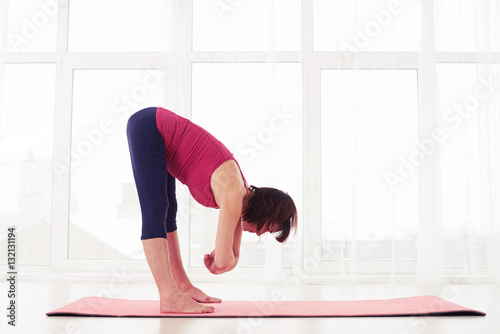 Yogi woman practising yoga lotus pose while meditating in the gy