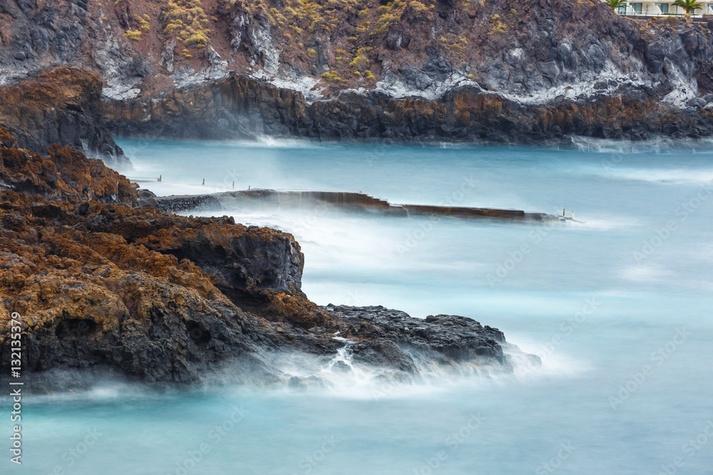 blue motion blur water surrounding rocks, long time exposure