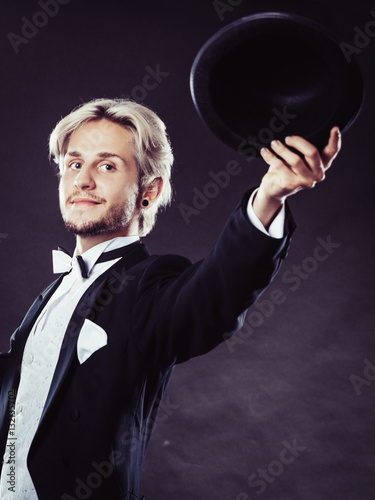 Elegantly dressed man throwing black fedora hat