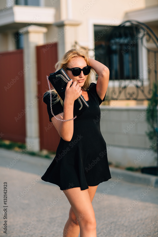 Portrait of beautiful blonde girl in black glasses and black dress. Hard light