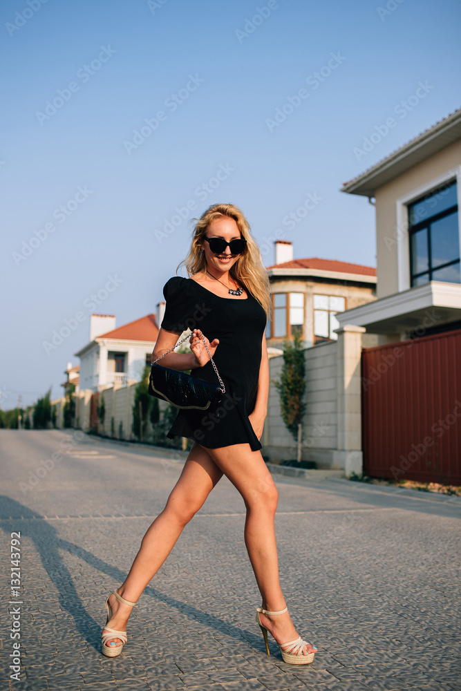 Obraz premium Portrait of beautiful blonde girl in black glasses and black dress. Hard light