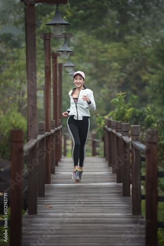 Young woman runner running on wood bridge