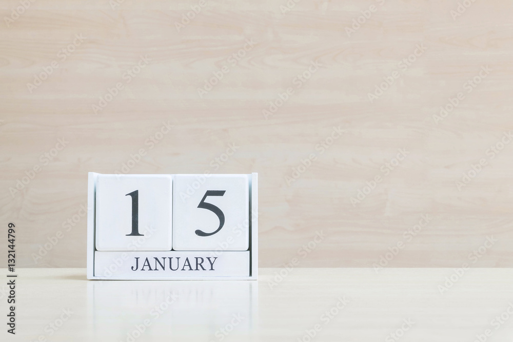 Closeup surface white wooden calendar with black 15 january word on blurred brown wood desk and wood wall textured background with copy space , selective focus at the calendar Closeup surface white wooden calendar with black 15 january word on blurred brown wood desk and wood wall textured background with copy space , selective focus at the calendar