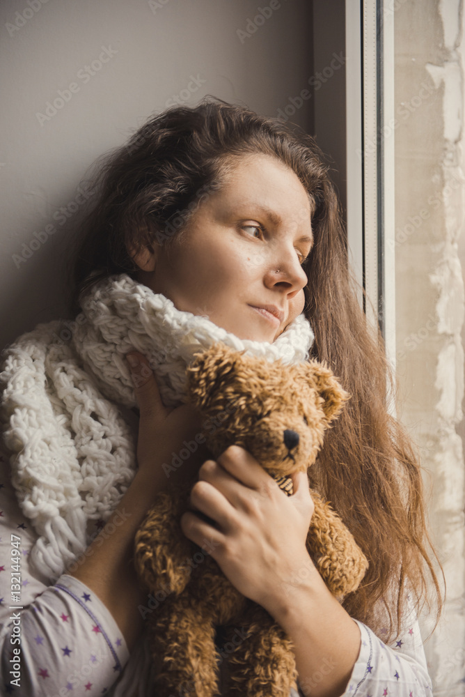 Sick girl sitting with a bear in the hands of the window. Sick girl sitting with a bear in the hands of the window.