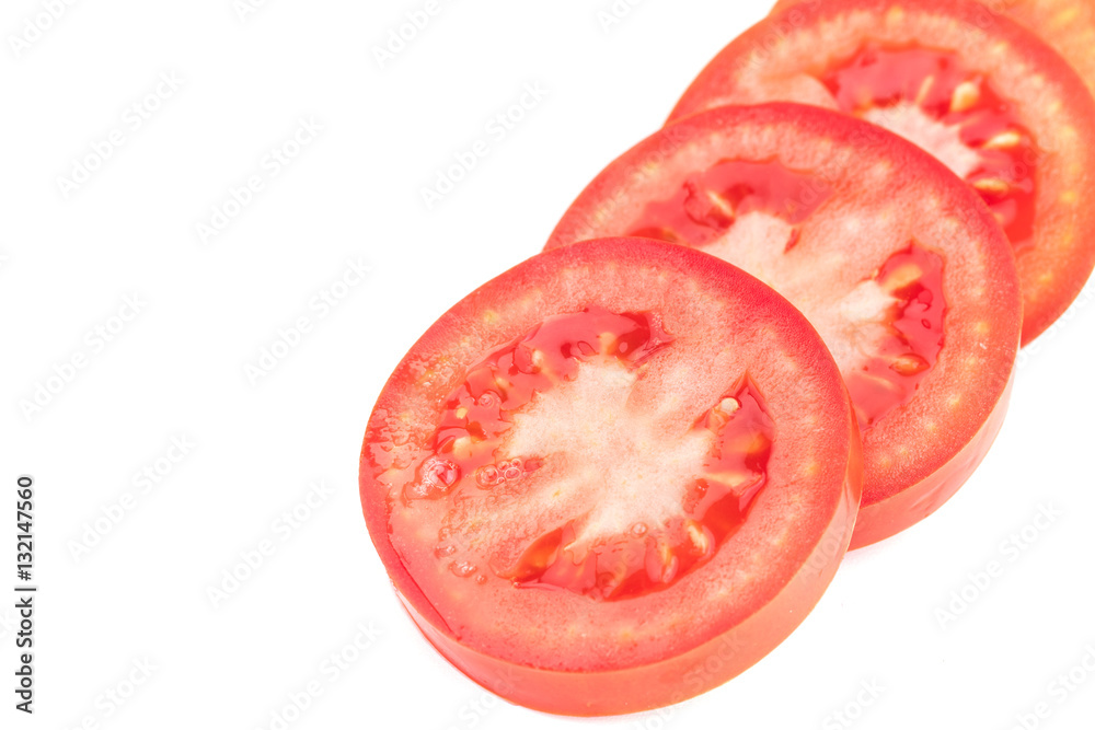 Closeup of red circular tomato slices layered and spread out on a white background Closeup of red circular tomato slices layered and spread out on a white background