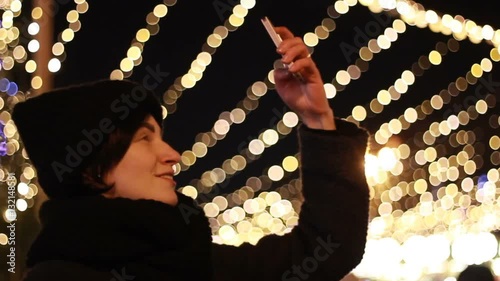 Girl holding a phone and taking a picture of a beautiful Christmas tree photo