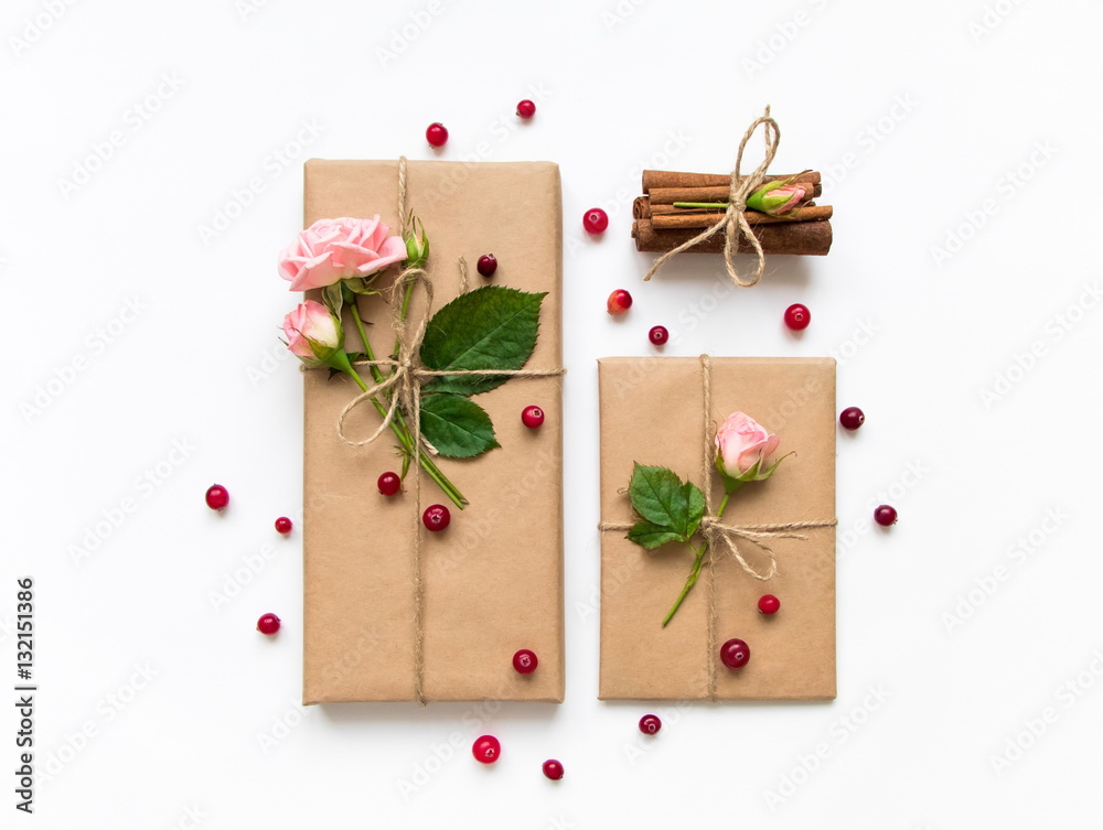 Gift box and envelope in eco paper on white background. Presents decorated with roses and berries. Holiday concept, top view, flat lay Gift box and envelope in eco paper on white background. Presents decorated with roses and berries. Holiday concept, top view, flat lay
