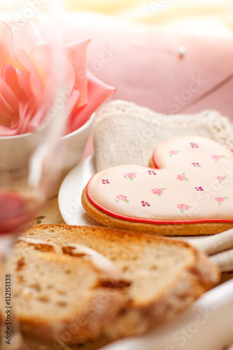 Romantic breakfast in bed. Breakfast tray with heart shaped biscuit, sparkling drink, rose and envelope.