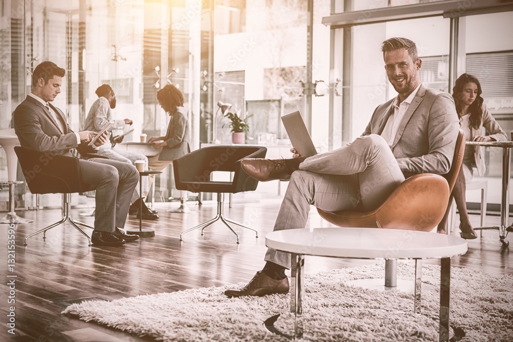 Obraz premium Smiling businessman using laptop in office