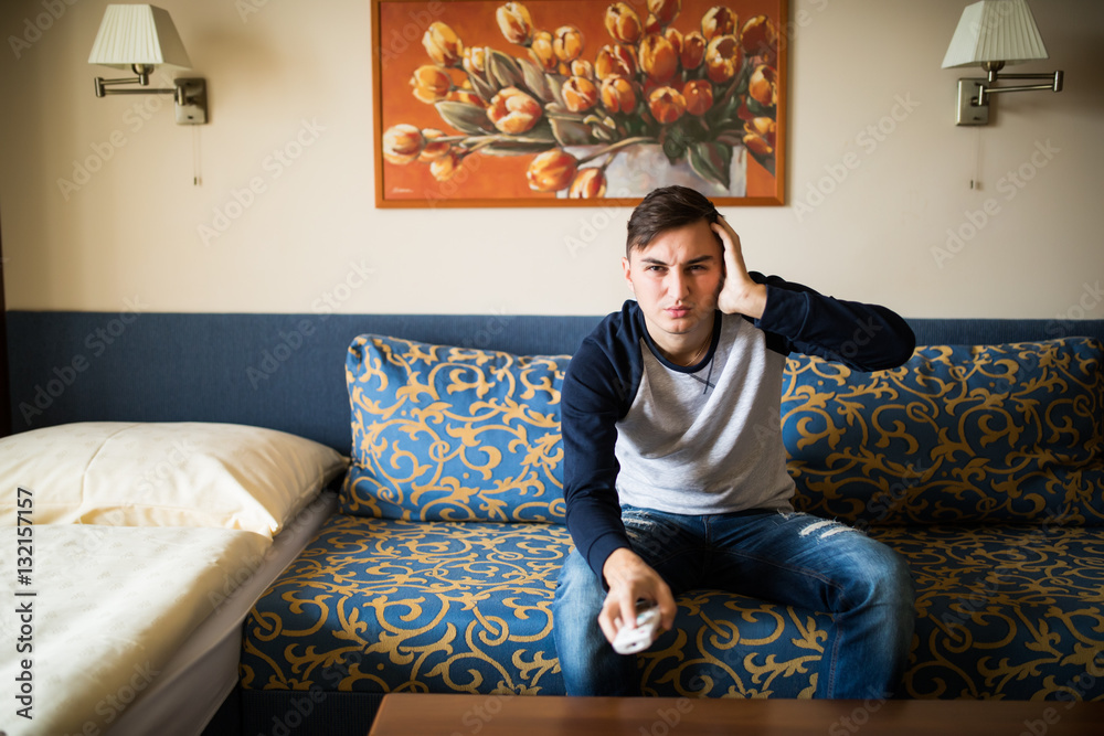 Obraz premium man on the couch watching tv, changing channels with emotions