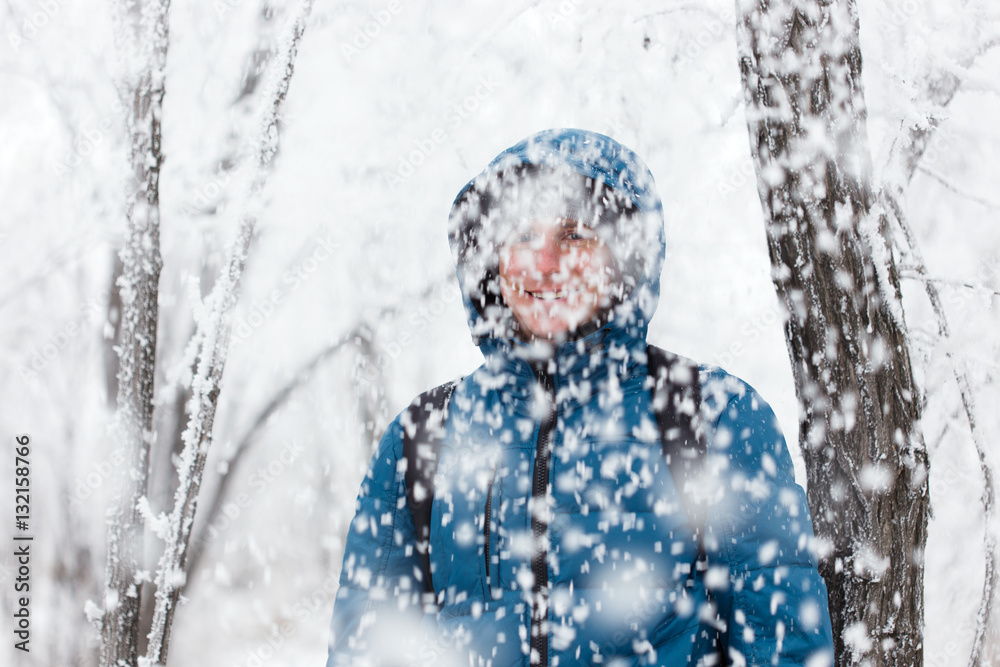 Young handsome man standing in snowfall on background of snowy forest. Young handsome man standing in snowfall on background of snowy forest.