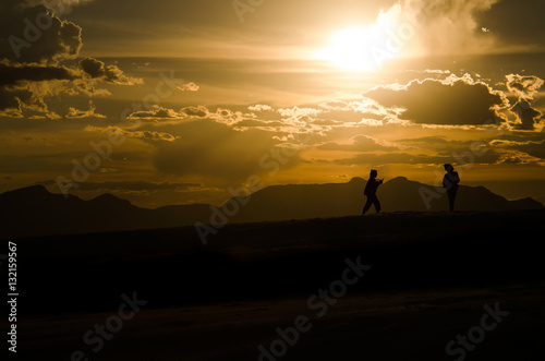 Silhouettes of two people walking on White Sand Dunes during sun