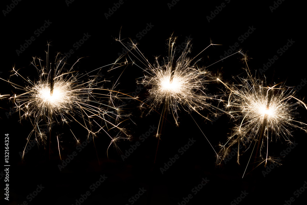 Three bright festive Christmas sparklers on black