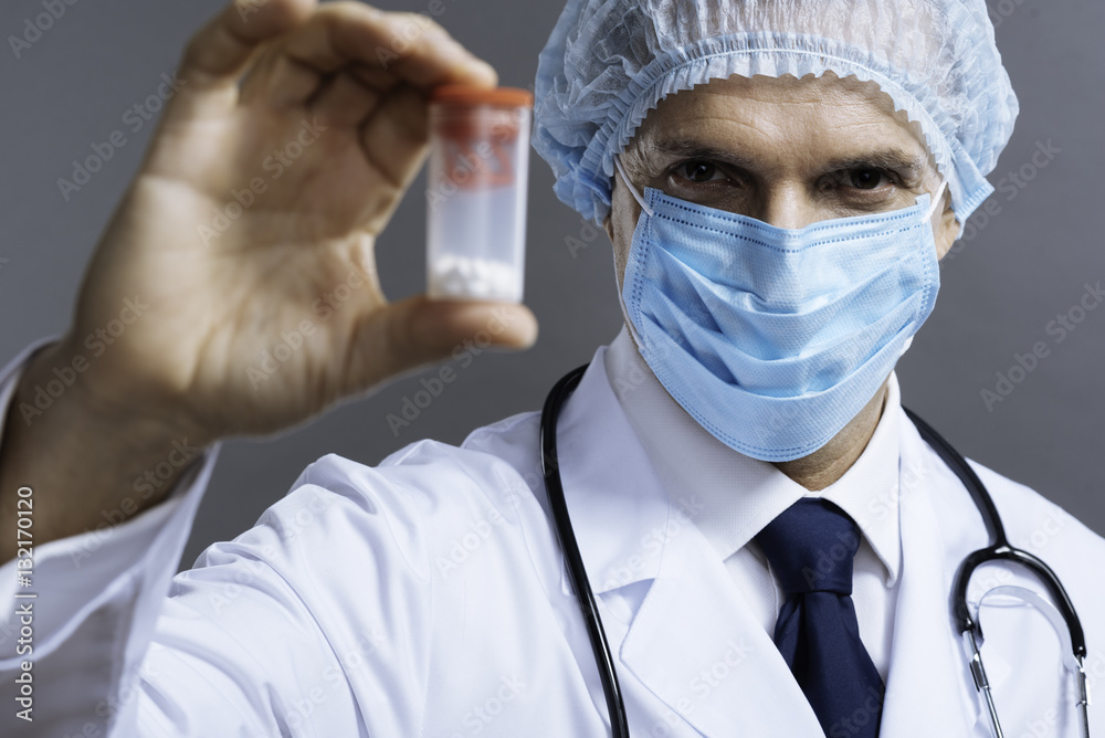 Handsome doctor in face mask posing with pills box Handsome doctor in face mask posing with pills box