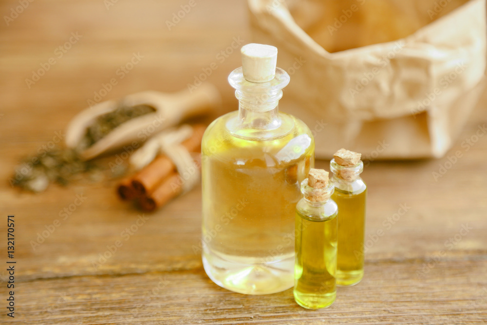 Bottles with tea oil on wooden background Bottles with tea oil on wooden background