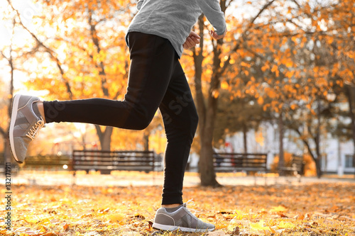Legs of young man running in autumn park