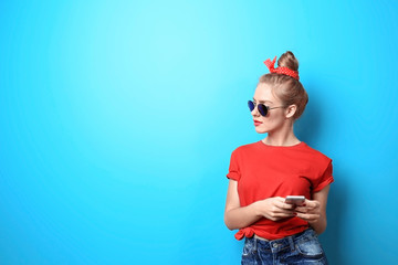 Young beautiful woman with smart phone on blue background