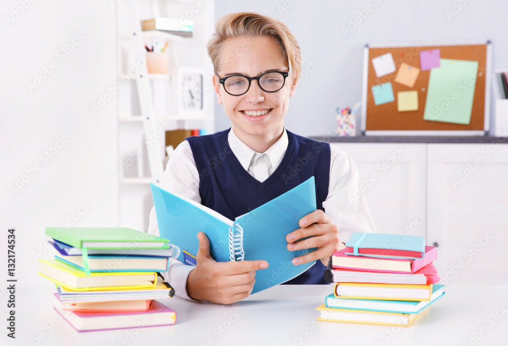 Pupil with pile of books sitting at desk in a classroom Pupil with pile of books sitting at desk in a classroom