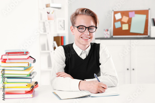 Pupil with pile of books si...