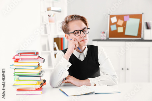 Pupil with pile of books si...
