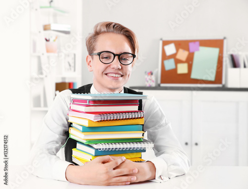 Pupil with pile of books si...
