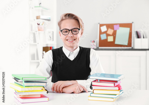 Pupil with pile of books si...