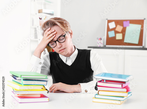 Pupil with pile of books si...