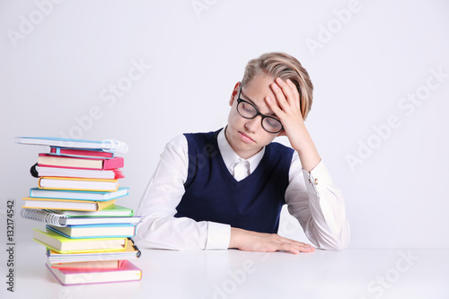 Pupil with pile of books si...