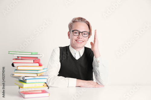 Pupil with pile of books si...