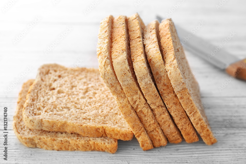 Sliced bread and knife on wooden background