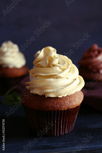 Tasty chocolate cupcake on wooden table against dark background, close up