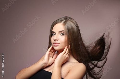 Young woman with healthy hair on color background