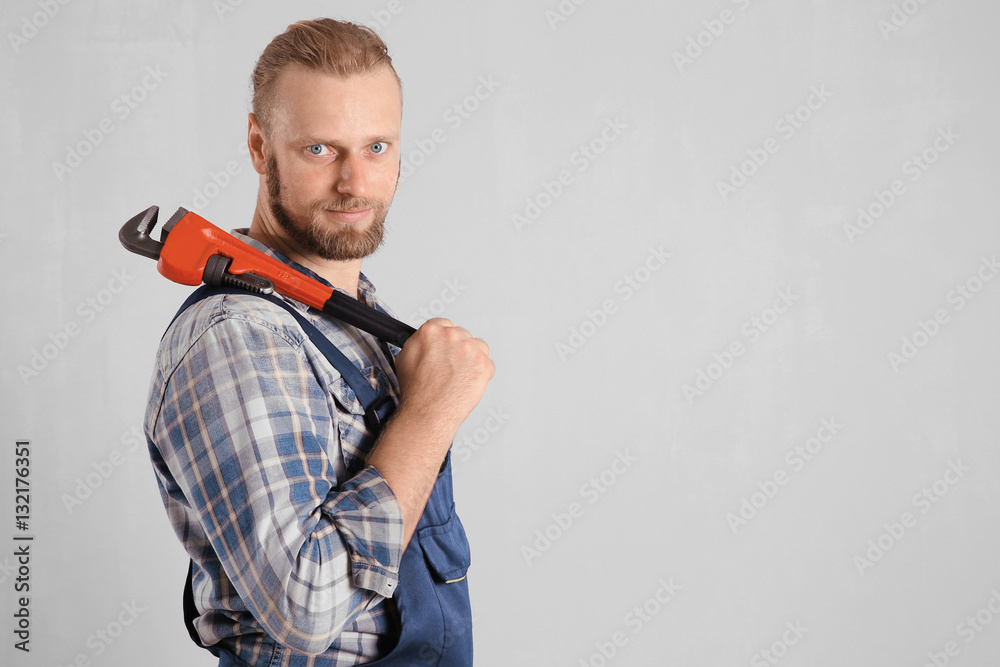 Portrait of handsome plumber with pipe wrench on light background Portrait of handsome plumber with pipe wrench on light background