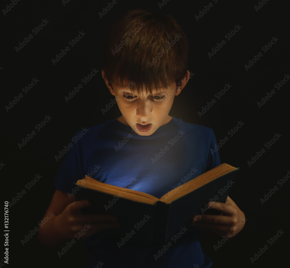 Cute boy reading book in darkness Cute boy reading book in darkness