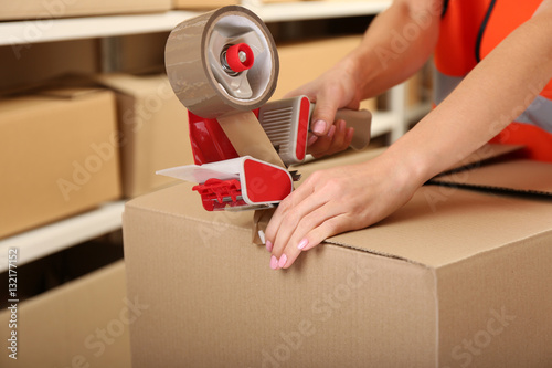Female hands packing box at warehouse, closeup photo