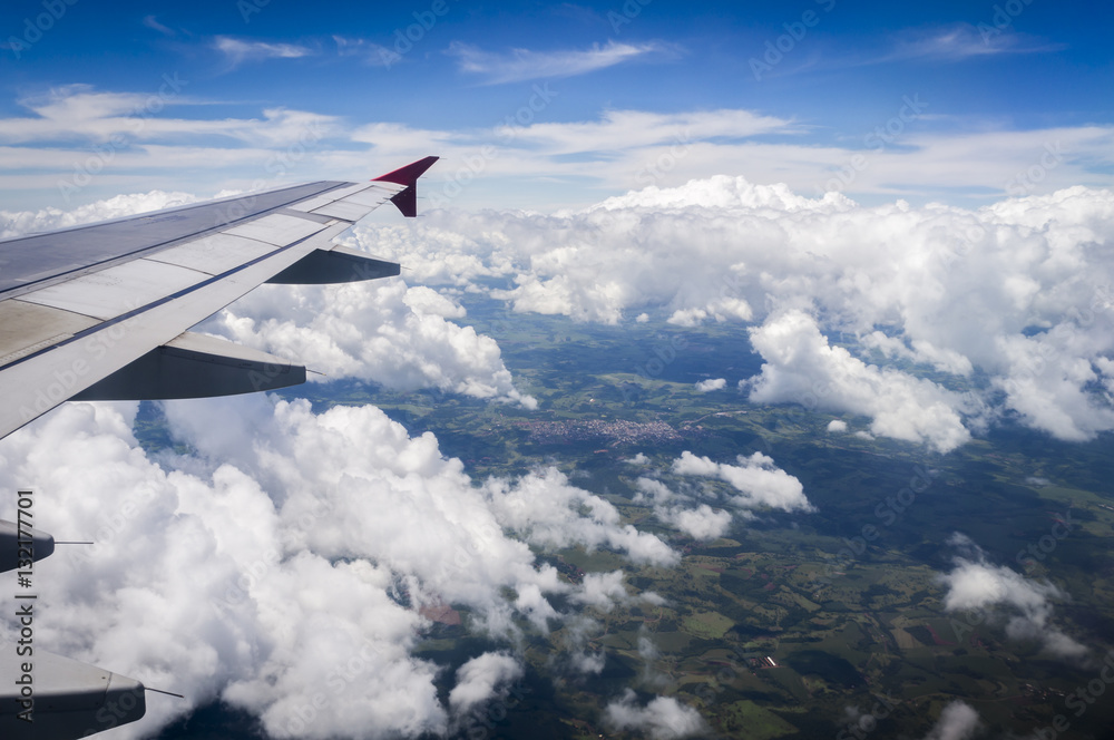 View from airplane window. Wing of an airplane flying above the clouds over Foz do Iguassu - Brazil View from airplane window. Wing of an airplane flying above the clouds over Foz do Iguassu - Brazil