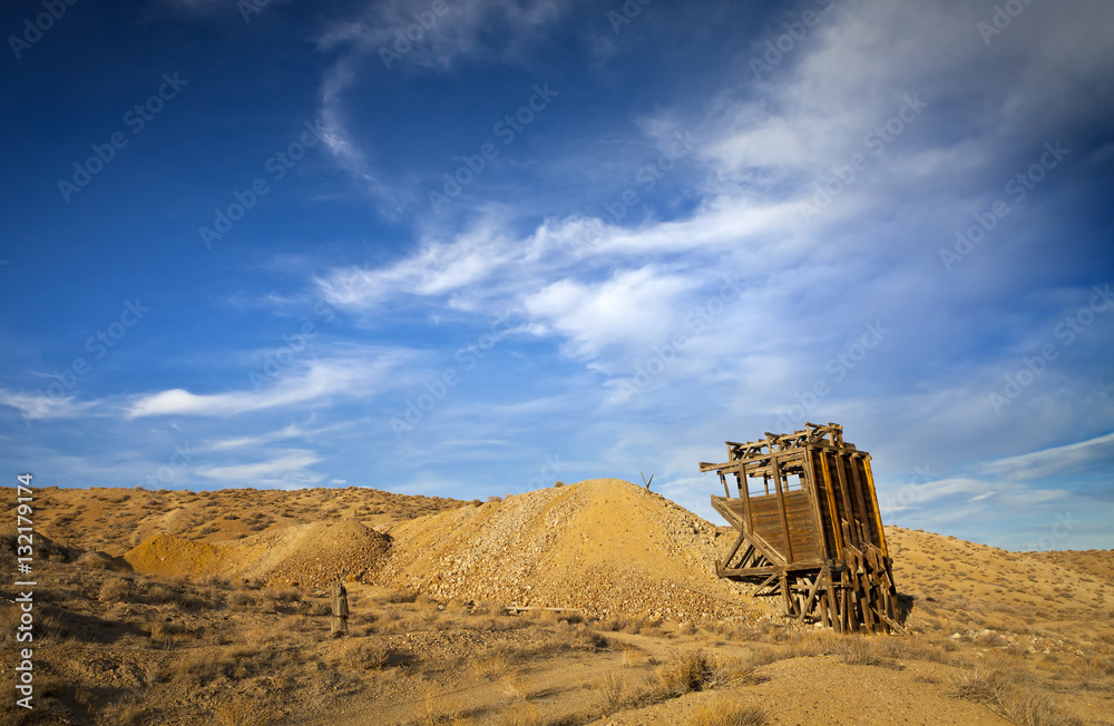 Old wooden mining hopper bin under blue sky in the Nevada Desert near a ghost town.