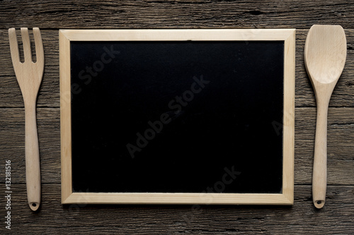 Empty blackboard with wooden fork and spoon on table background