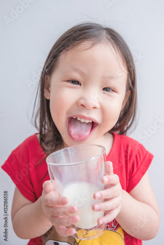 Little asian girl smiles after drinking milk from glass