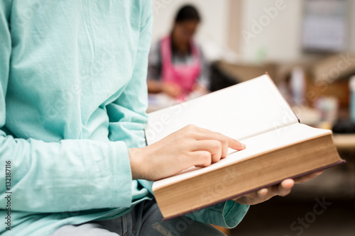 Asian young girl close up finger pointing to reading a book at o